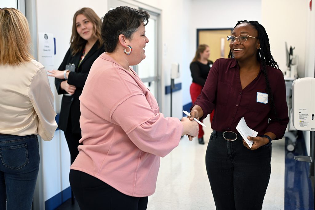 A social work student greets a patient's family member.