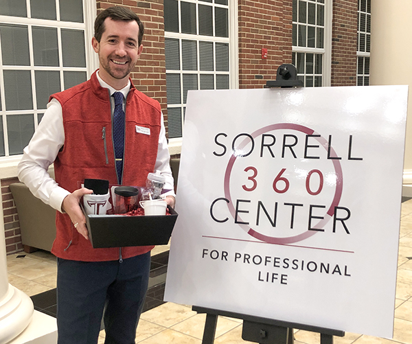 Lecturer Preston Pritchett, program coordinator for the Sorrell 360 Center, shows off a gift basket that students could win by registering for a professional development seminar. (TROY photo)