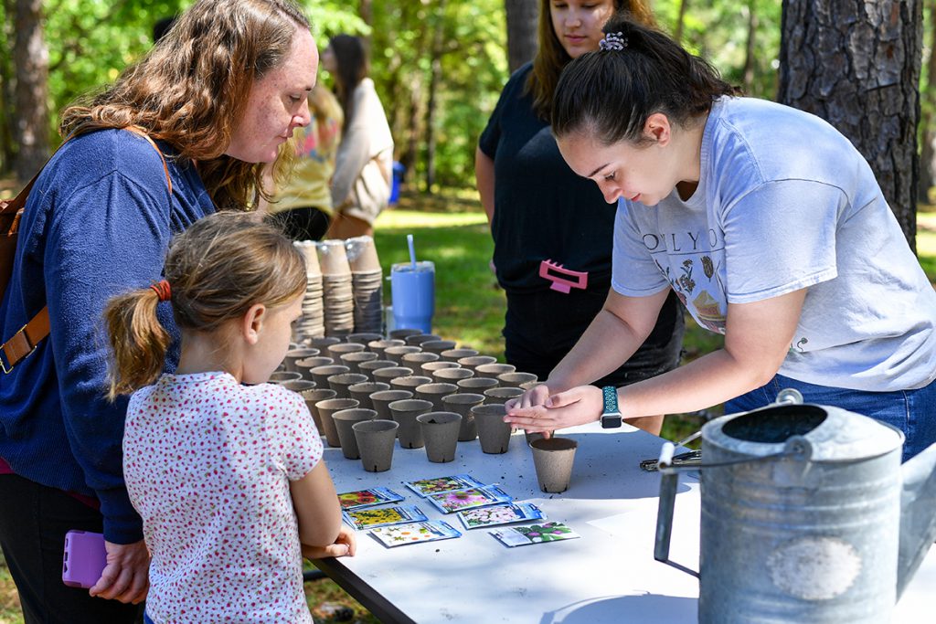 A TROY student helps a young girl plant flower seeds during the 2023 Earth Day festival.