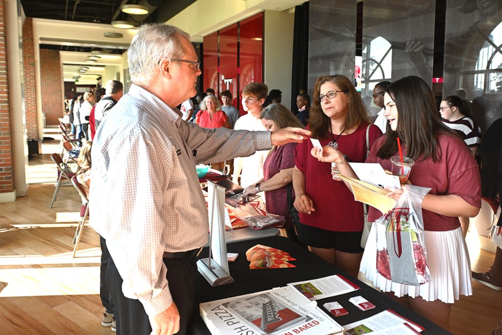 A prospective student and her family talk with a professor at the Sorrell College of Business table