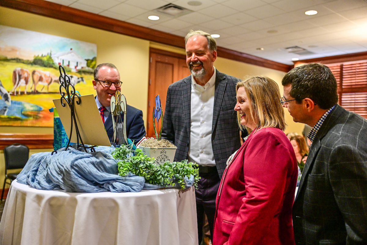 Vardaman surrounded by colleagues and with her husband admiring the retirement gifts given to her by the School of Nursing.
