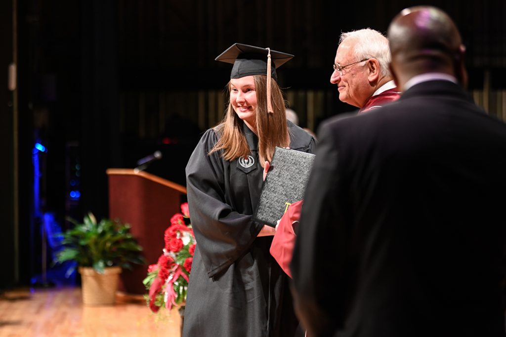 A student receives her diploma from Chancellor Hawkins.