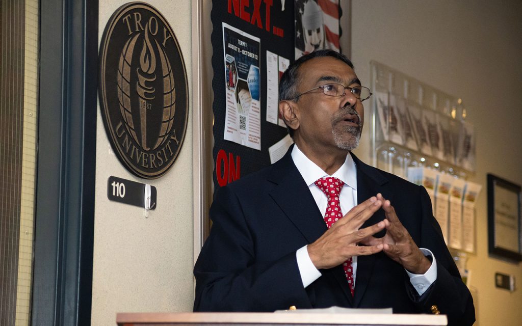 Sohail Agboatwala, Senior Vice Chancellor for Student Services and Administration, speaking at a podium during a ceremony celebrating TROY’s new partnership with Shaw Air Force Base to offer on-base classes for service members. 