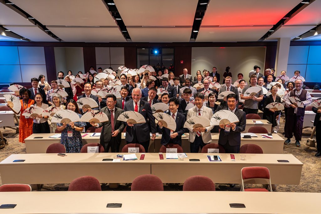 Ceremony attendees pose with fans gifted by the Korean delegation.