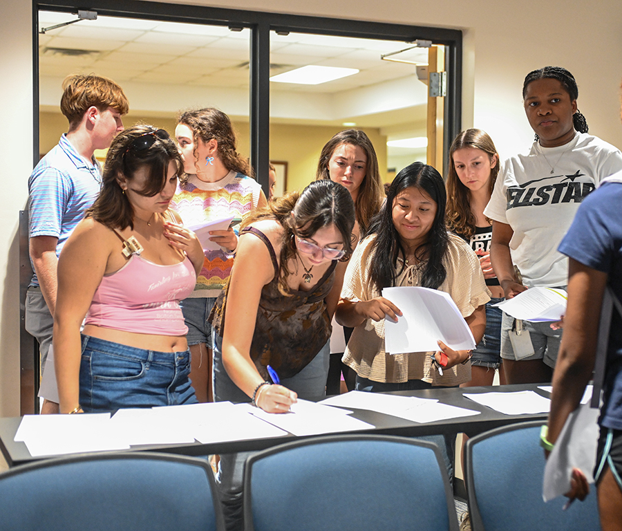 Students sign sign-up sheets after the interest meeting concluded.