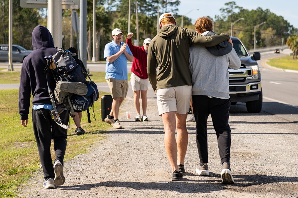 ATO walkers lean on each other for support as they approach a rest station.