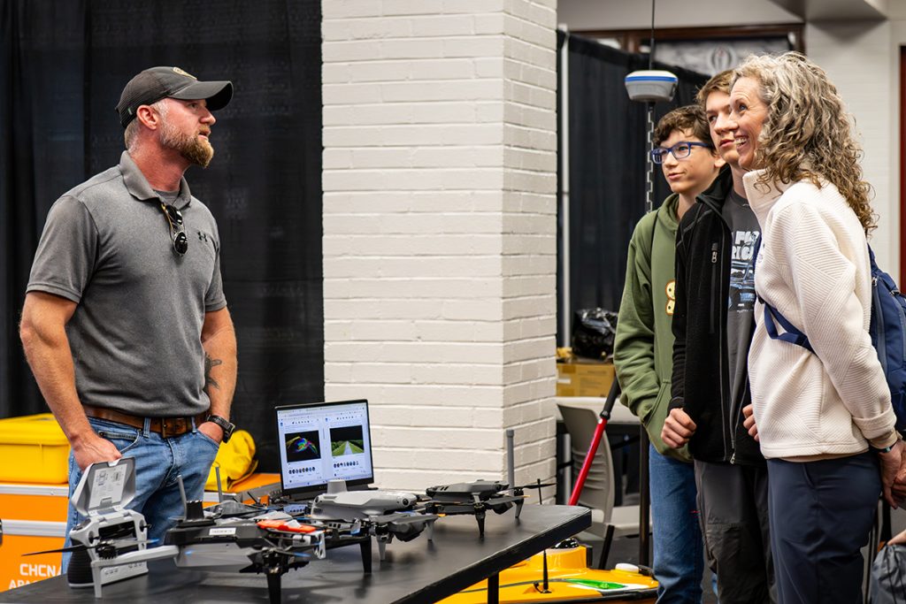 A high school counselor and her students observe the table of drones at Geo Day 2026.