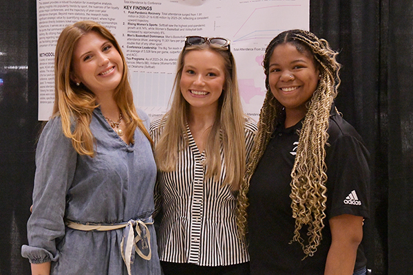 A photo of three students in front of a research poster