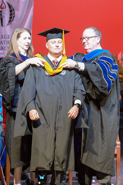 Joshua Bunger receives his hood for the Master of Science in Nursing at the spring commencement ceremony on the Montgomery Campus on May 21.