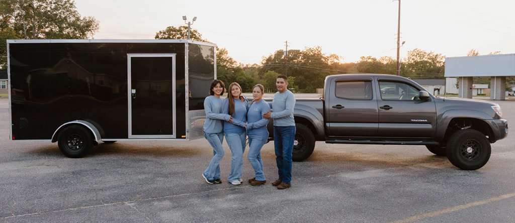 a family of four in front of a truck and trailer