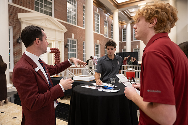 a photo of a faculty member speaking to students at a table